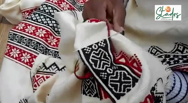 Close-up of hand embroidery in red and black thread on cotton cloth